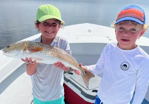To young boys holding up a fish they caught while spending the day with Fishing Charters in St. Petersburg FL